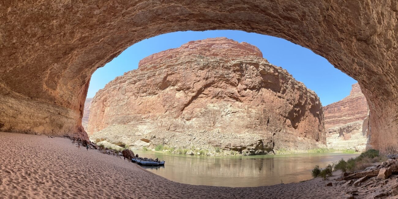 View from inside Redwall Cavern toward the Colorado River and a raft on the sandy beach
