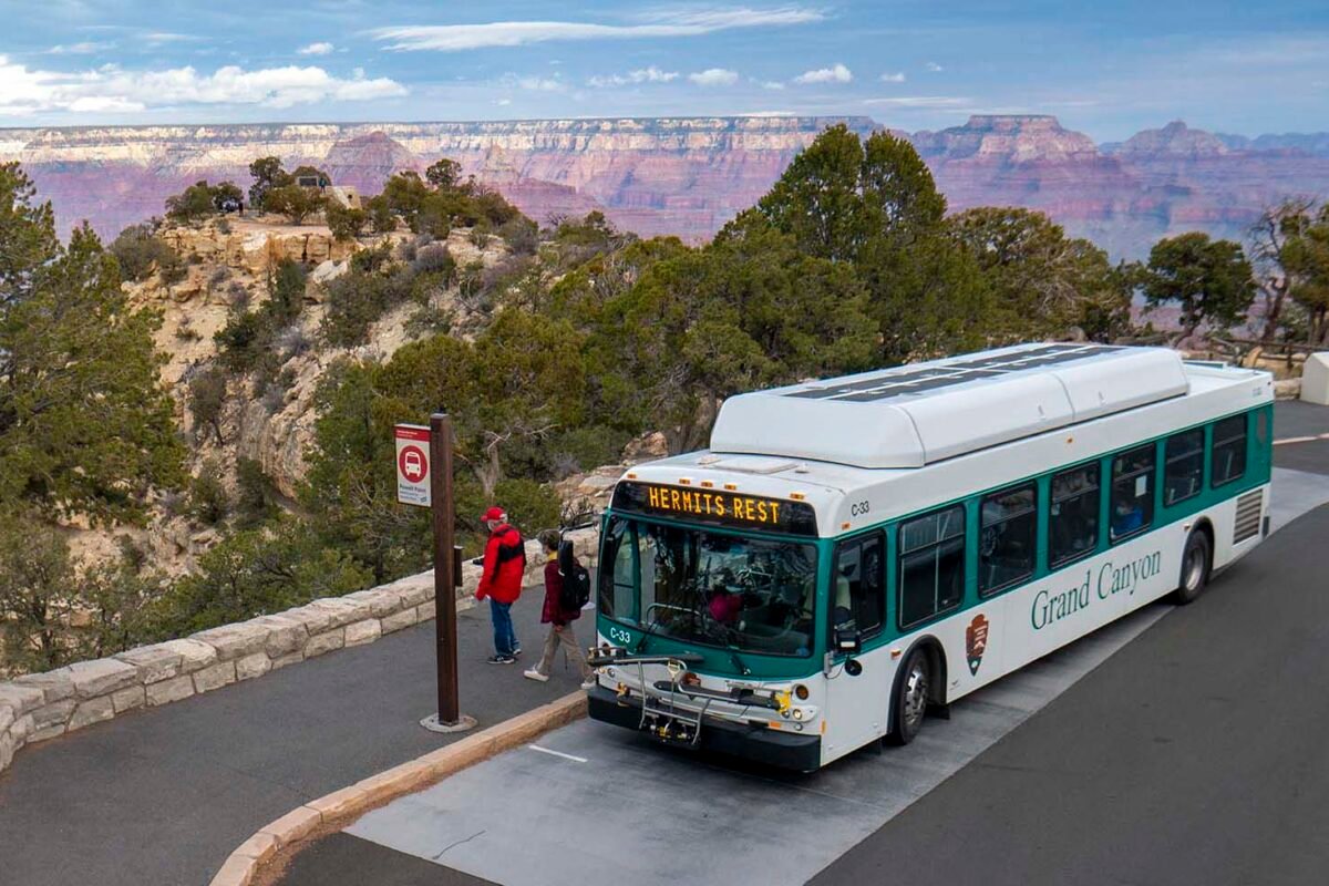 Grand Canyon shuttle bus at a Hermit Road stop with the canyon behind it