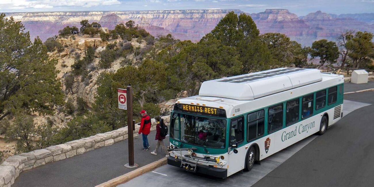Grand Canyon shuttle bus at a Hermit Road stop with the canyon behind it