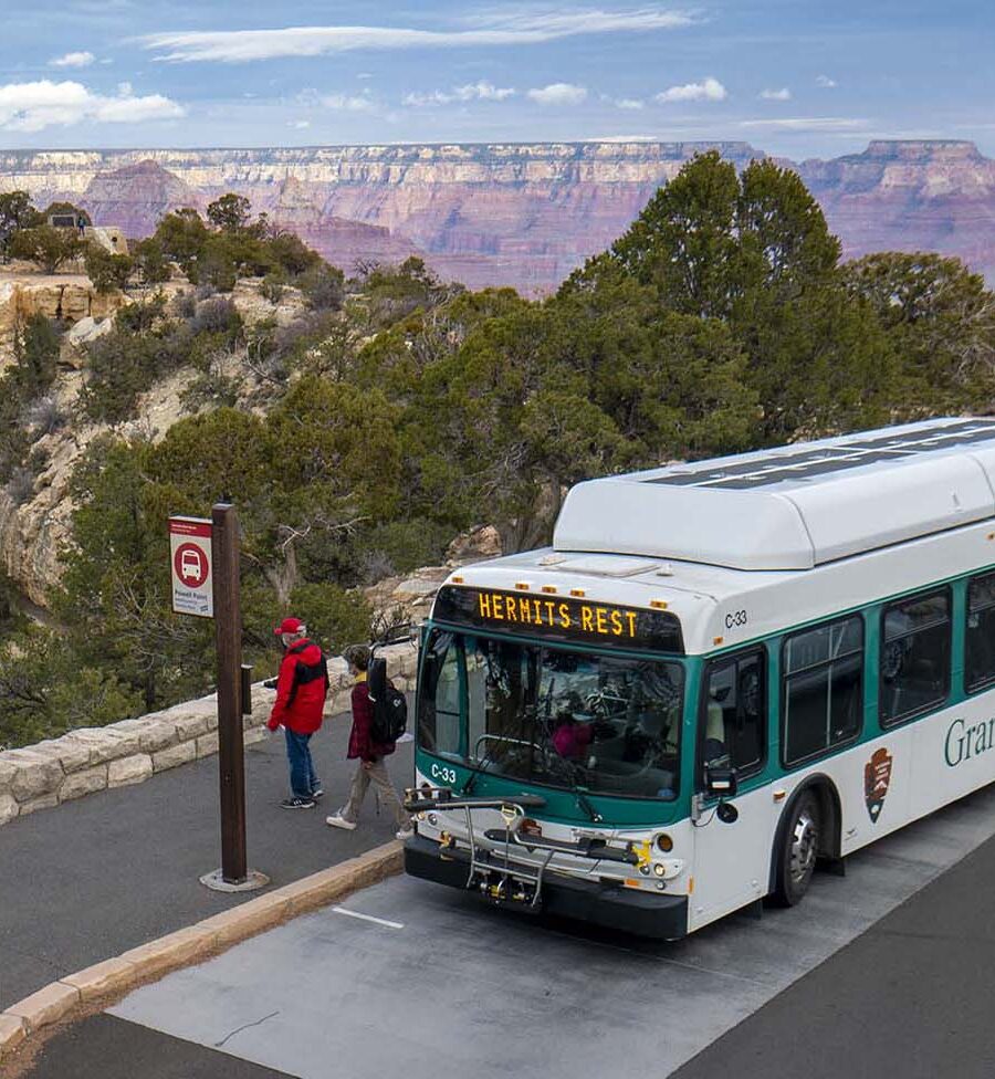 Grand Canyon shuttle bus at a Hermit Road stop with the canyon behind it