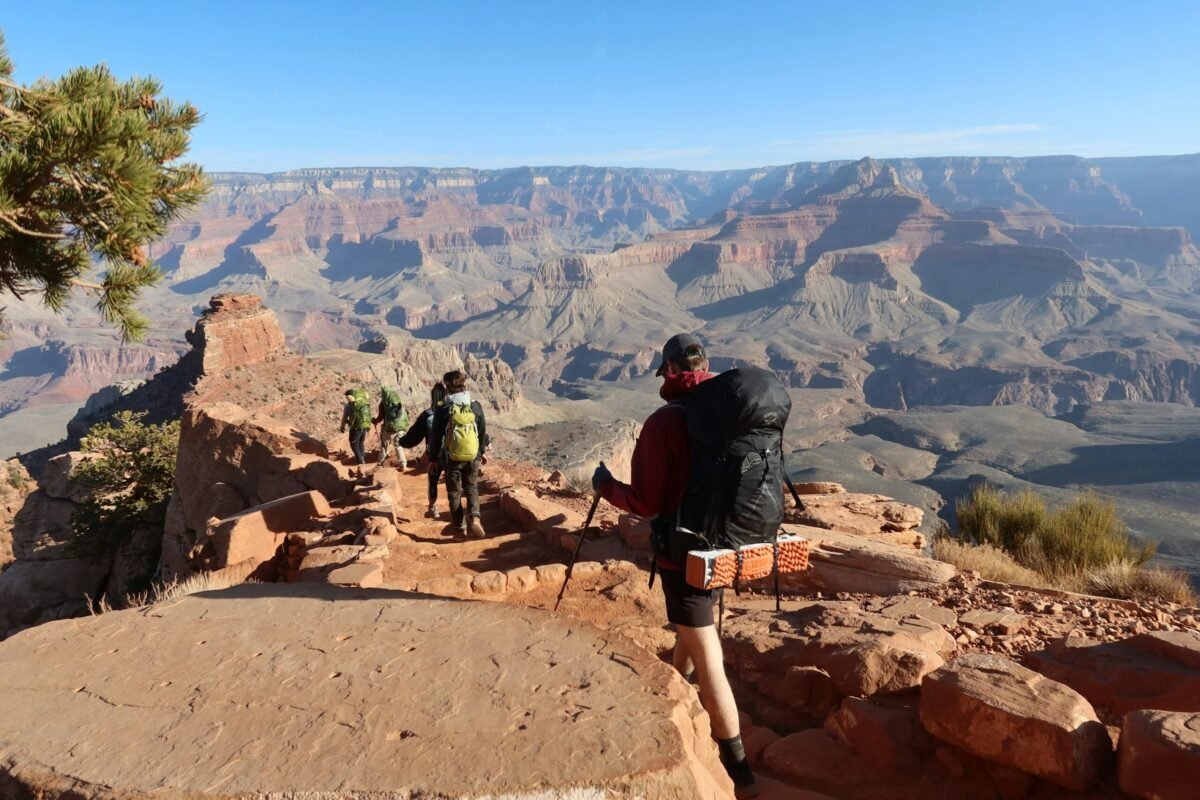 Hikers descending a Grand Canyon trail with layered canyon walls beyond