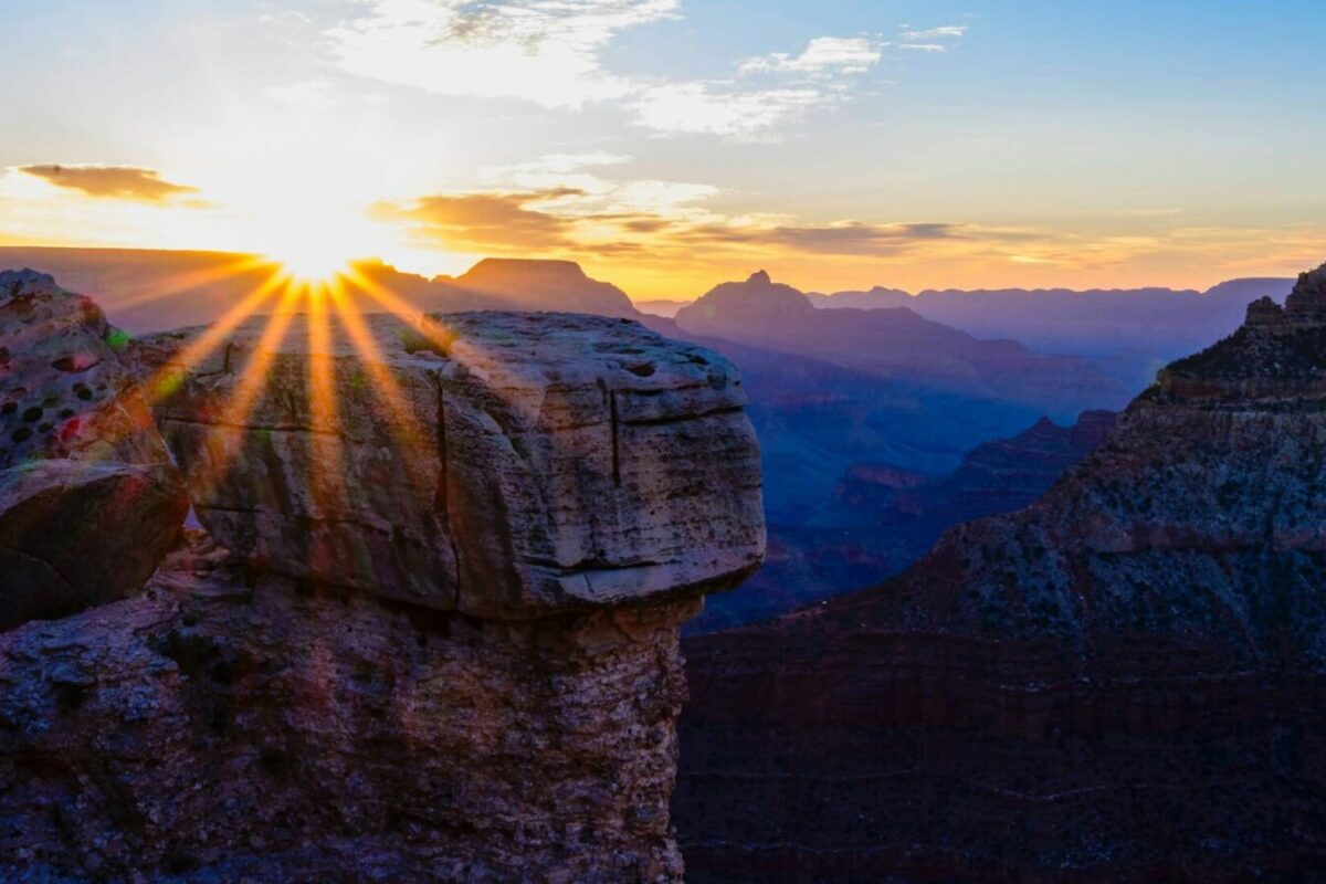 Sunrise breaking over foreground cliffs and the Grand Canyon South Rim