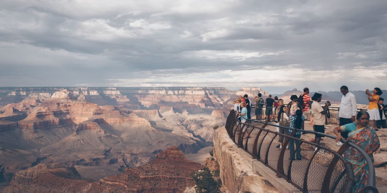Visitors looking across the Grand Canyon from a rim overlook at sunset