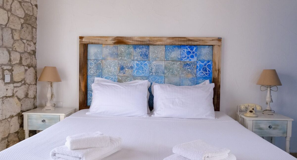 Hotel room with white linens, stone wall, and rustic decor