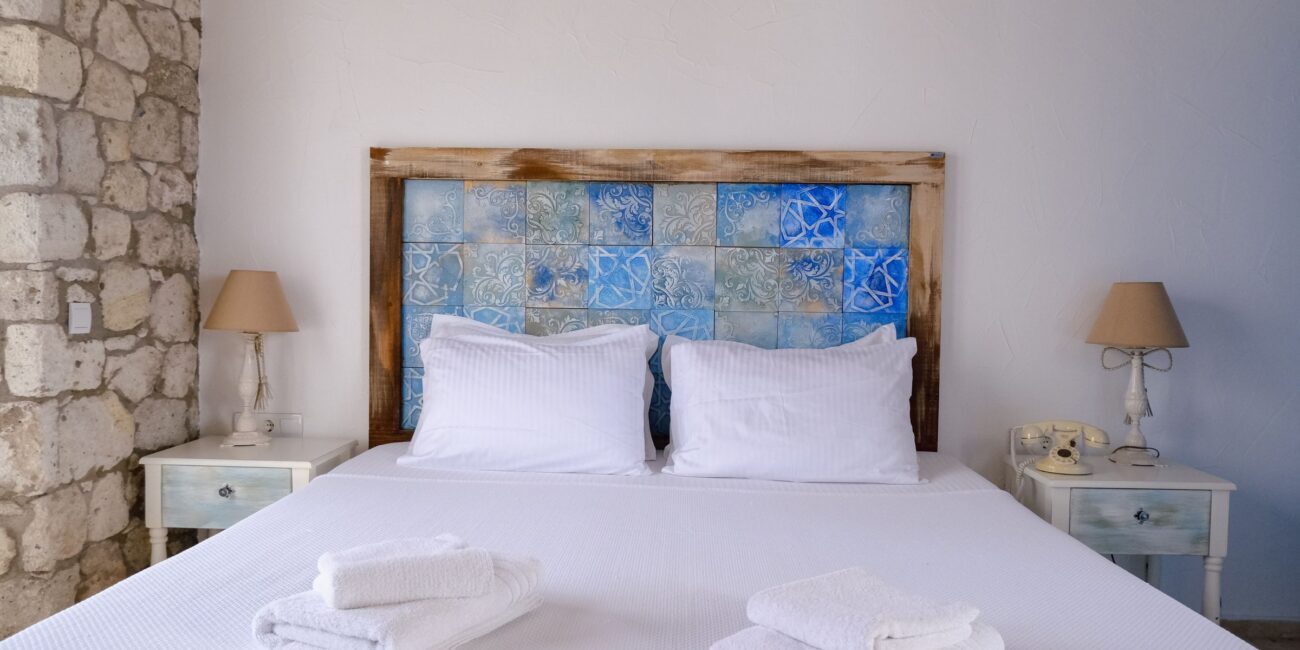 Hotel room with white linens, stone wall, and rustic decor