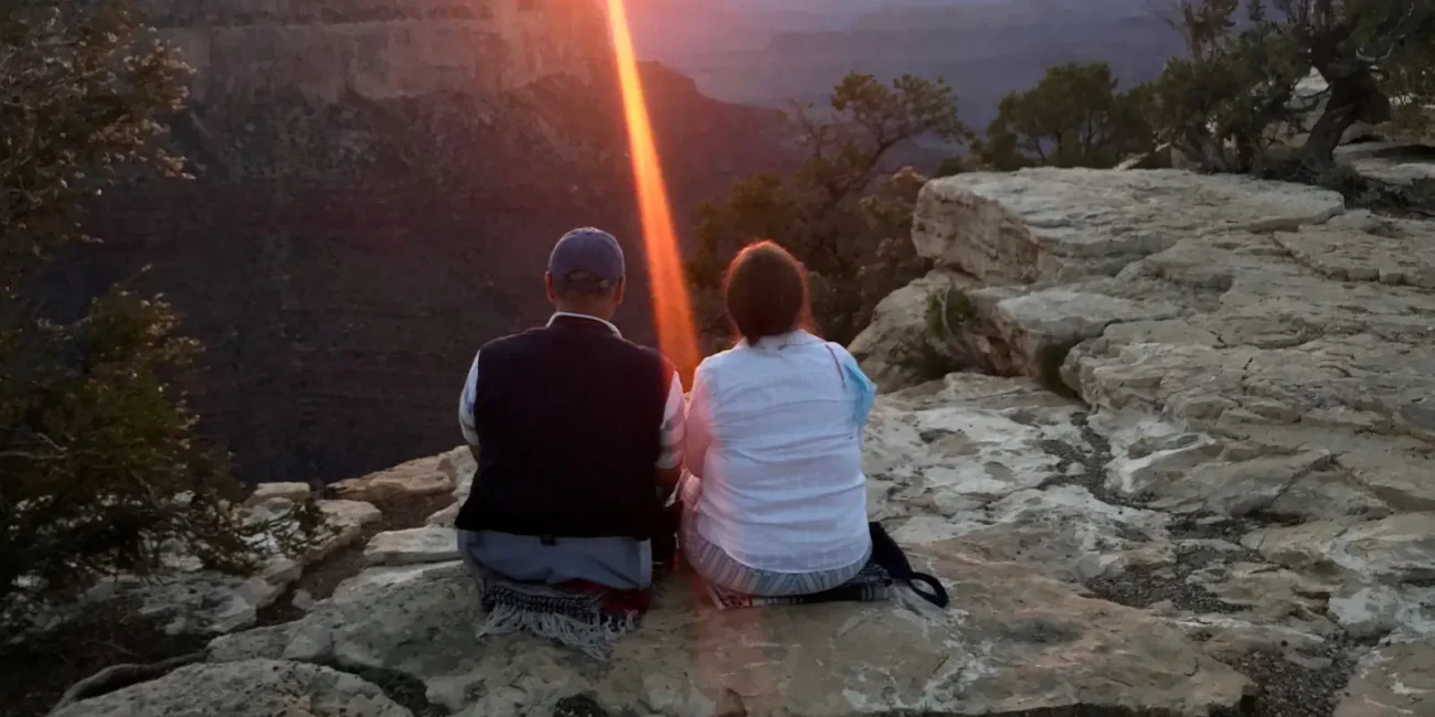 Two visitors watching sunset over the Grand Canyon