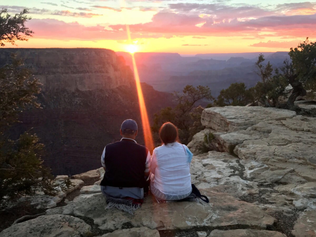 Two visitors seated on a Grand Canyon overlook at sunset